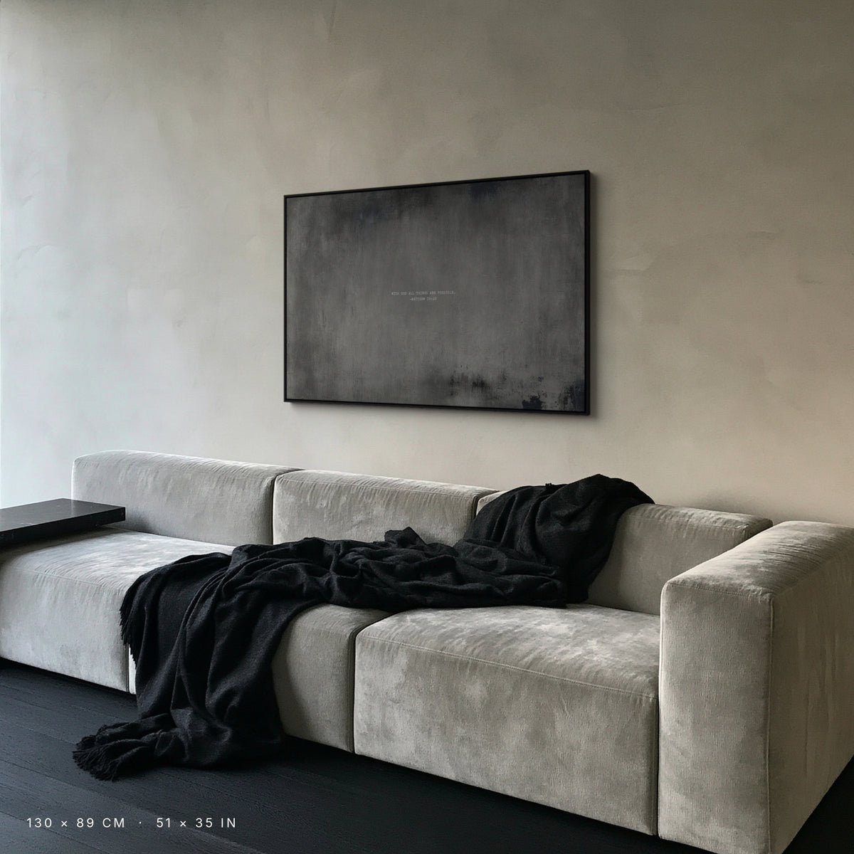 Graphite canvas, 130 × 89 cm, black floating frame, above a grey velvet sofa in an Amsterdam living room